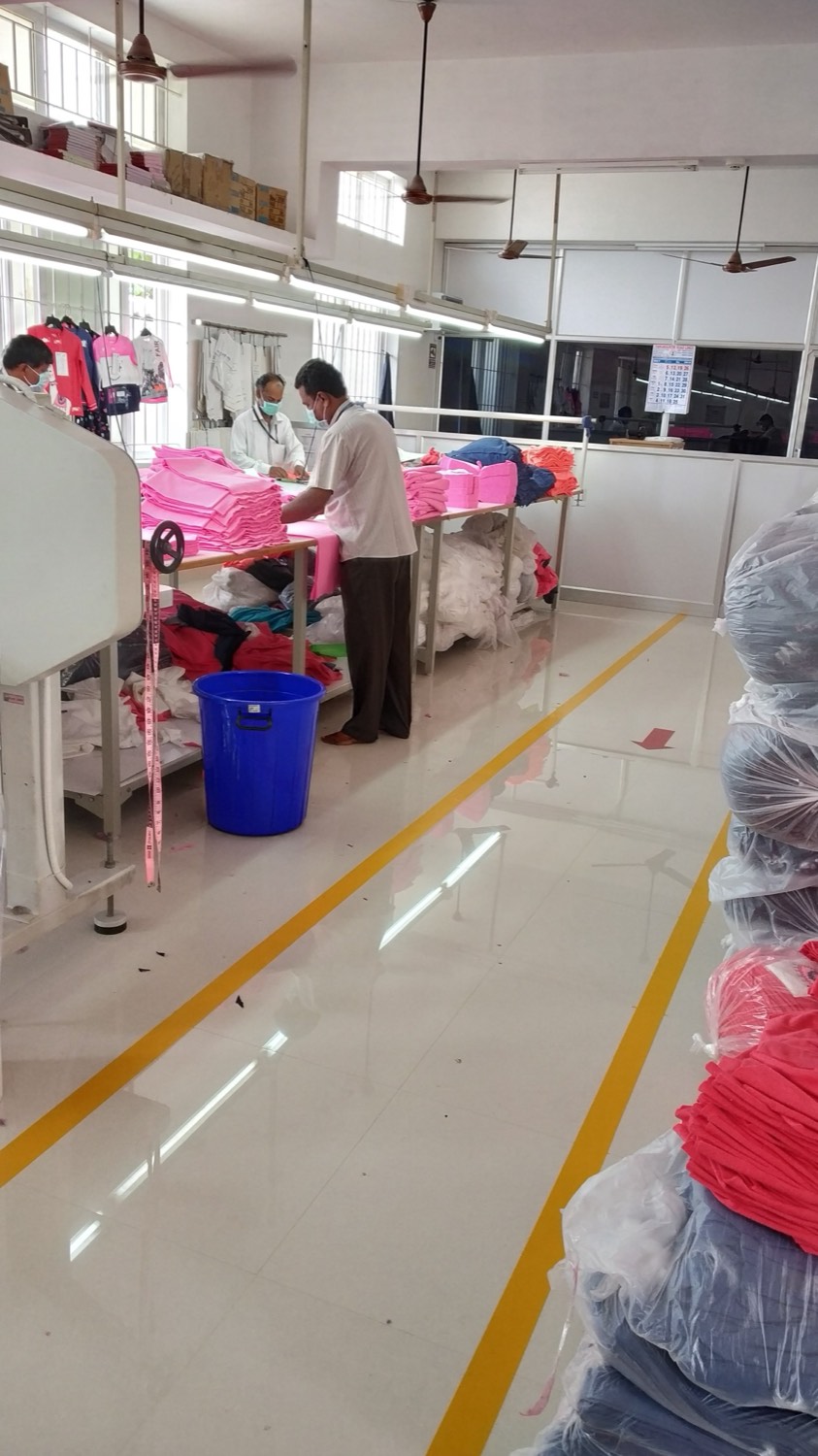 Fabro operators checking and folding finished garments at inspection tables on the production floor