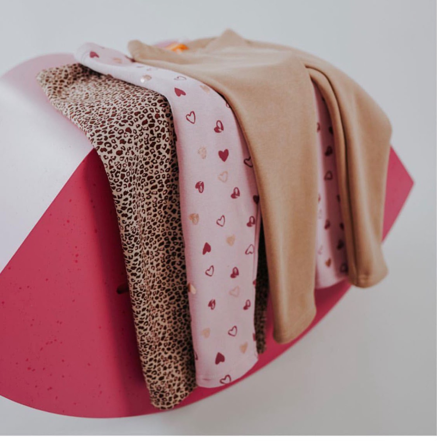 Printed and plain knitted fabrics from Fabro, showing a leopard print, a foil heart print and a plain camel