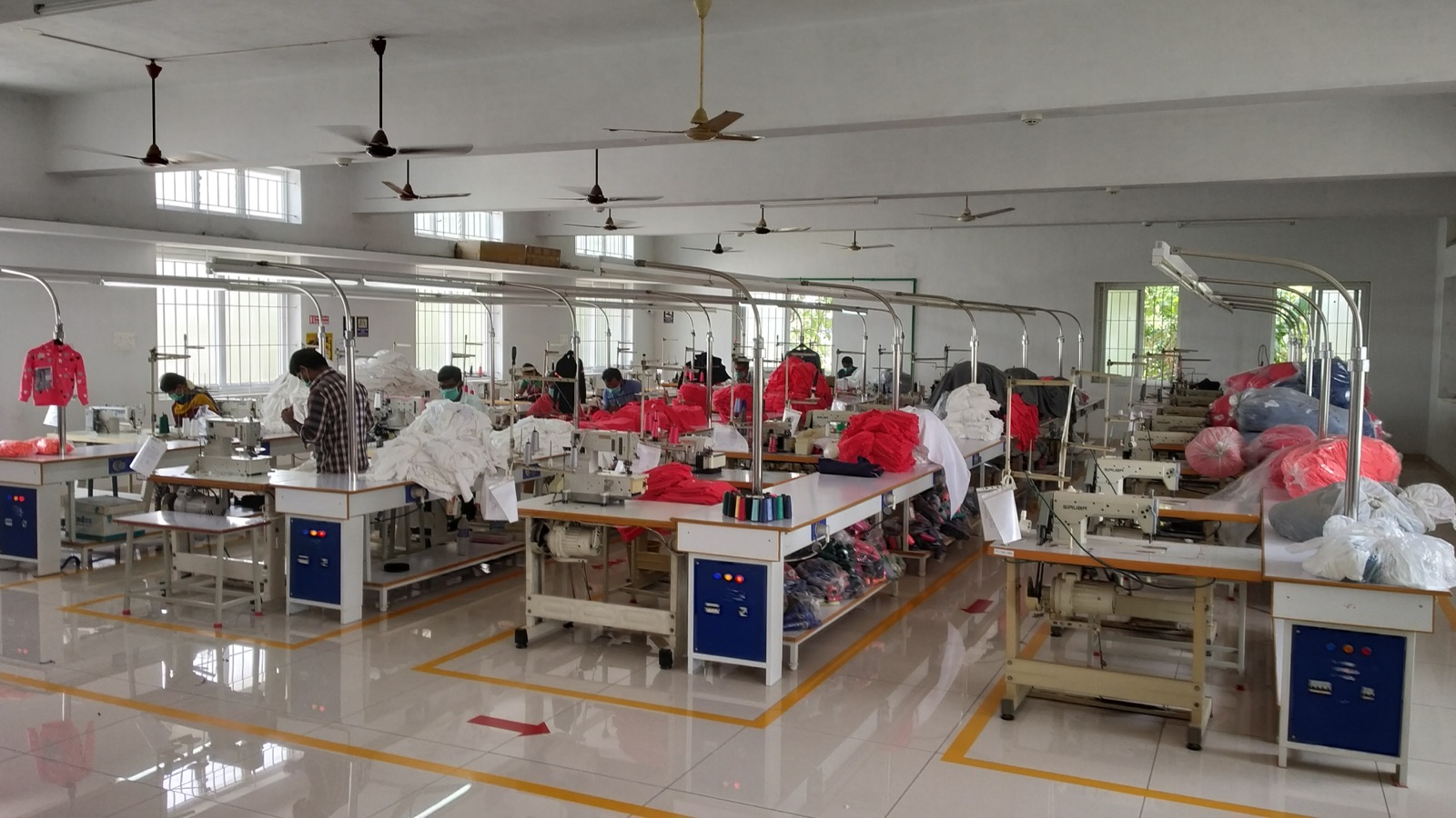 The Fabro sewing floor in Tirupur, rows of machines with operators working on red and white garments