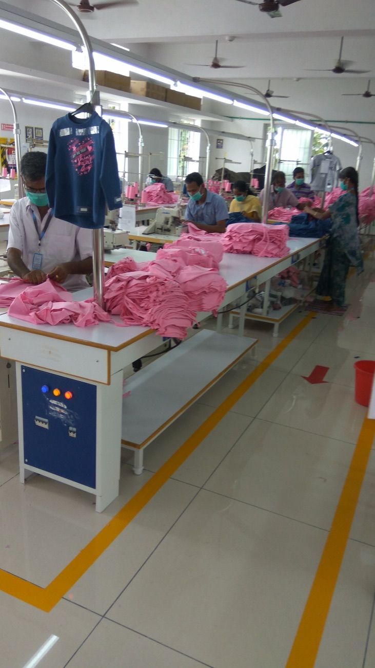 Fabro operators at the sewing line, stitching and stacking pink knitted garments under task lighting